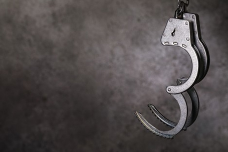 Open handcuffs against the background of a concrete wall as a symbol of a pardon