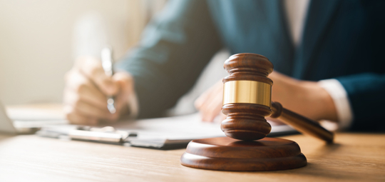 Gavel on desk with attorney blurred in the back