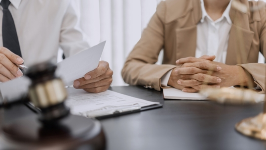 Image of a lawyer and client sitting at a table looking over paperwork