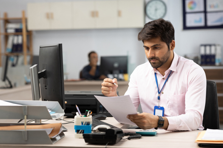 Businessman with computer reading documents in office