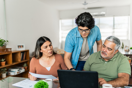 Family talking over the details of immigration paperwork on laptop at home