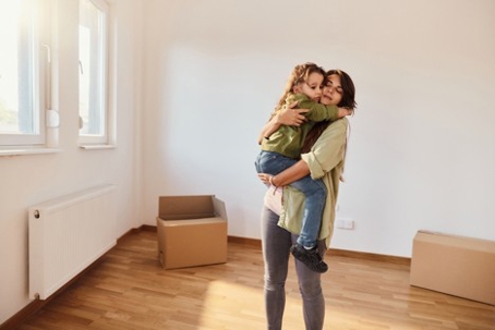 Mother holding her small girl after moving into a new apartment.