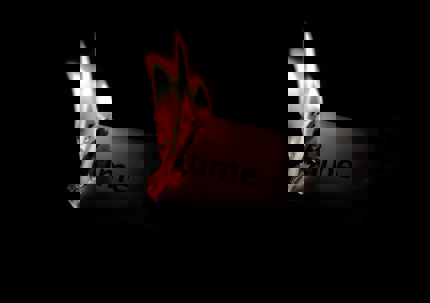 A hand holds a piece of paper with the word “time” as the edge burns with bright flames against a dark background.